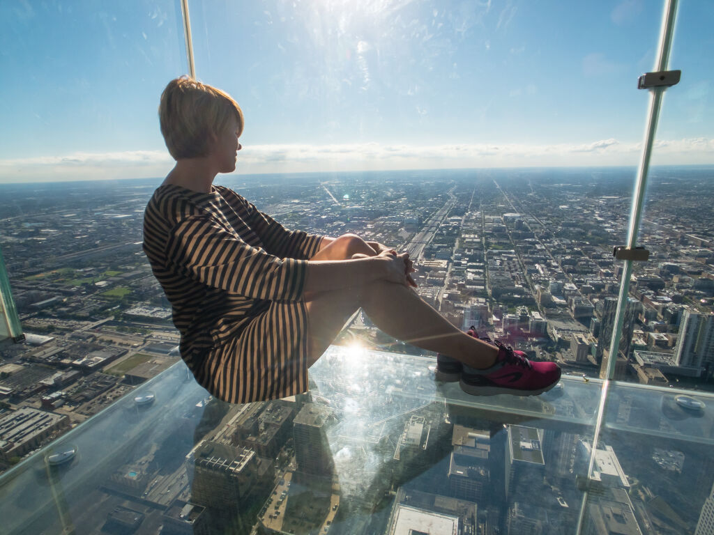 Tourists posing on a glass floor in a skyscraper